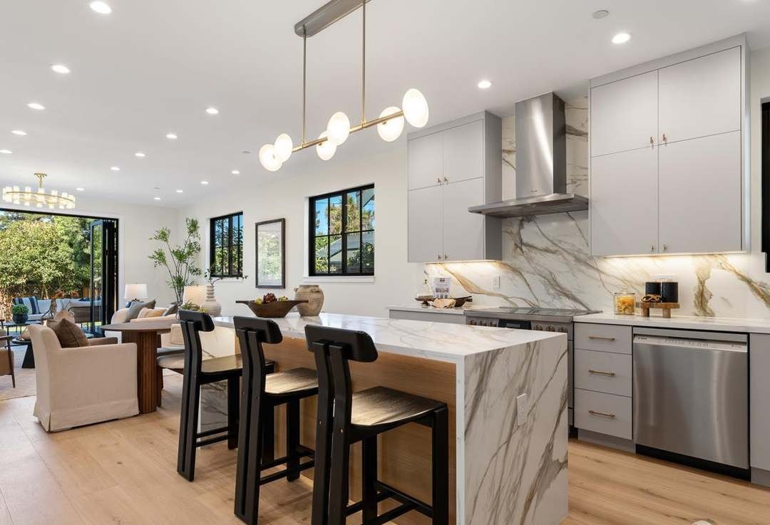 Kitchen with marble waterfall island and brass pendant